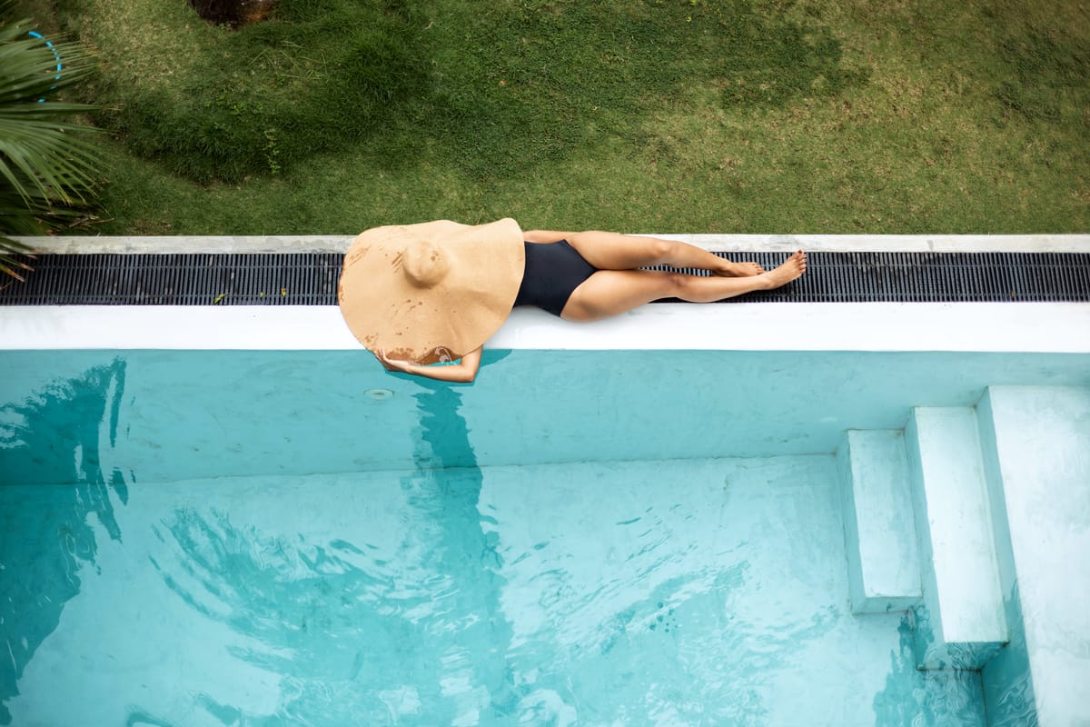 From above: a swimmer in a straw hat in the turquoise pool