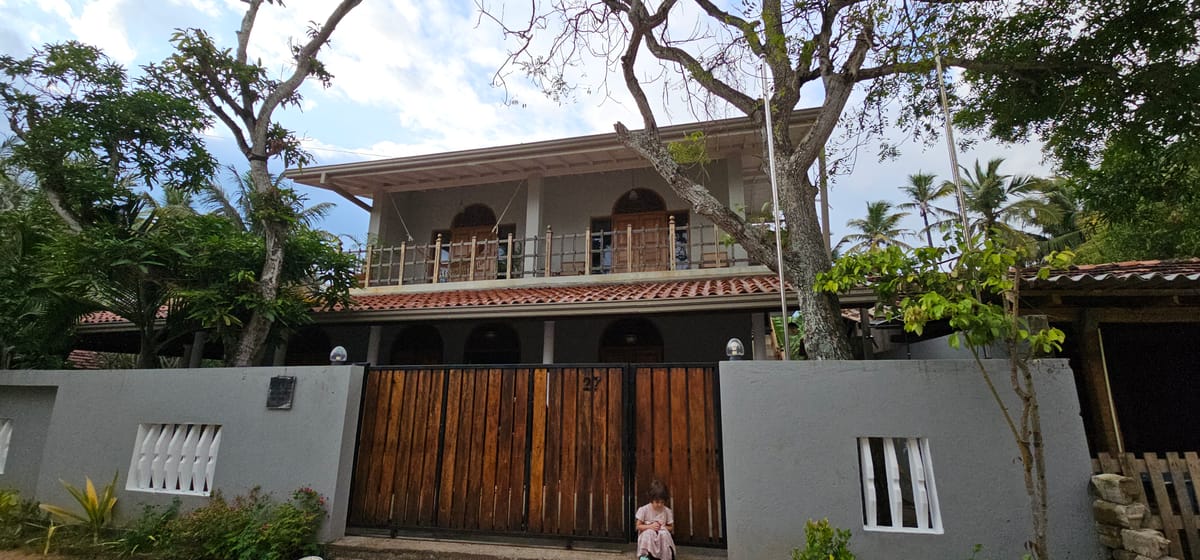 La villa vue de la rue, son portail de bois et son étage à arcades